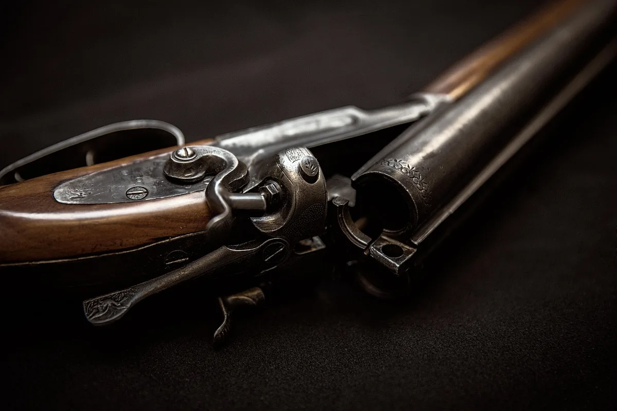 Main avec pistolet à mastic au-dessus d'un carrelage, outils et tasseau flou en arrière-plan